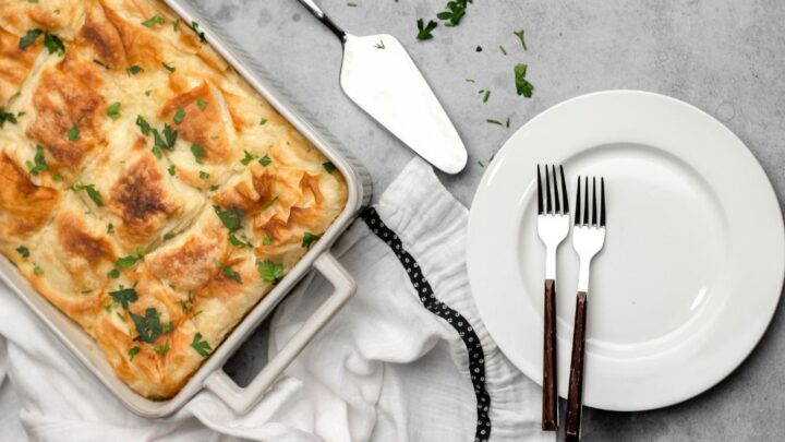 tray of panakopita on table near plate with 2 forks