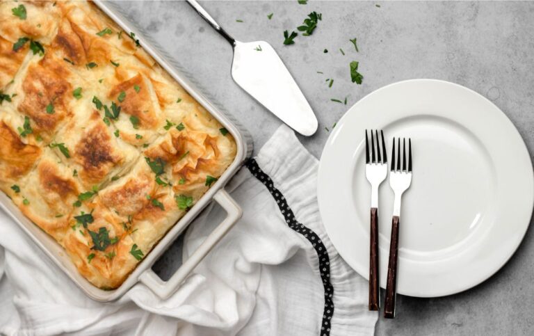tray of panakopita on table near plate with 2 forks