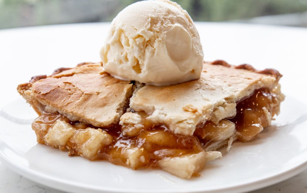 piece of mango peach pie with one scoop of vanilla ice cream on top