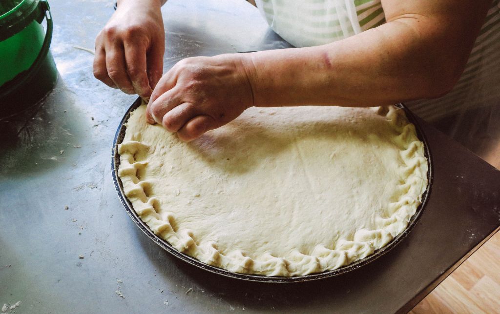 woman sealing peach mango pie before baking