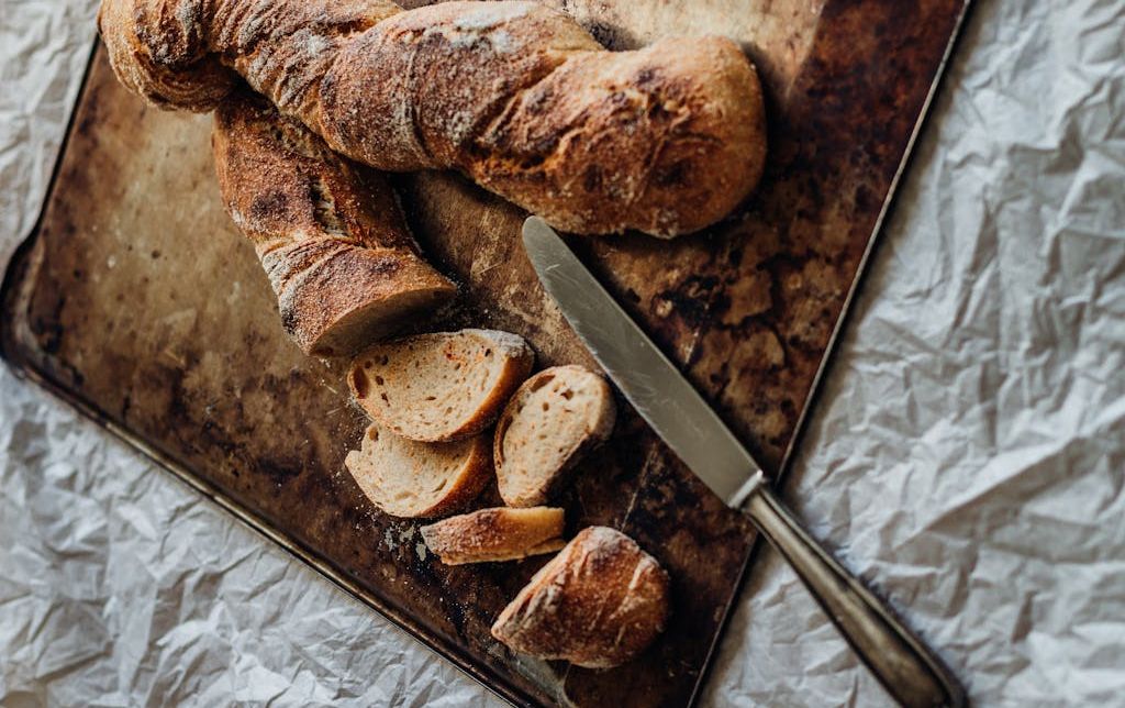baguette partially sliced on a wooden plate