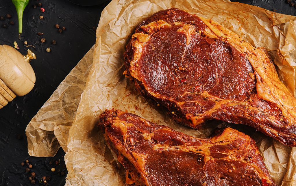 2 raw t bones marinated on a paper