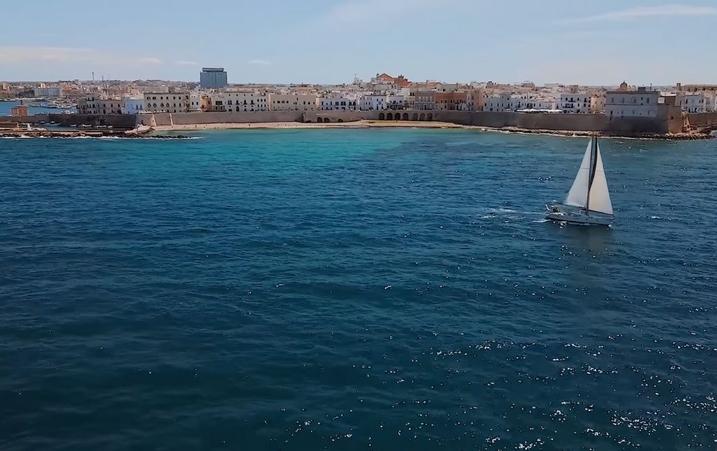 long sandy beach seen from the see, a boat is sailing on the sea