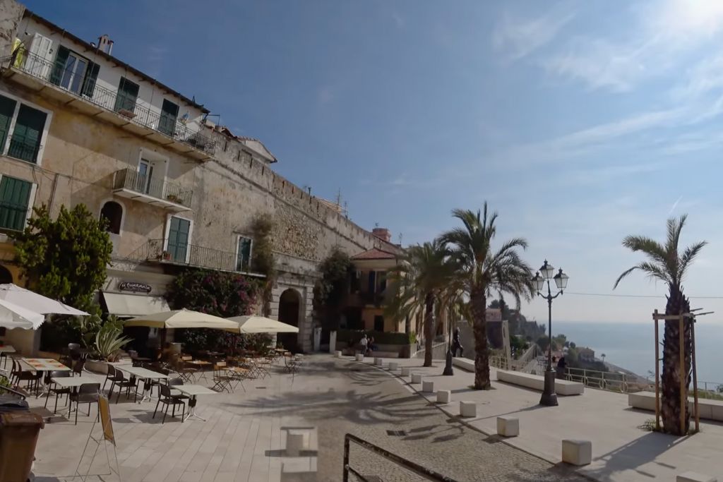 stone piazzetta on the shore of the sea, terrace in the piazzetta and an old building next to it