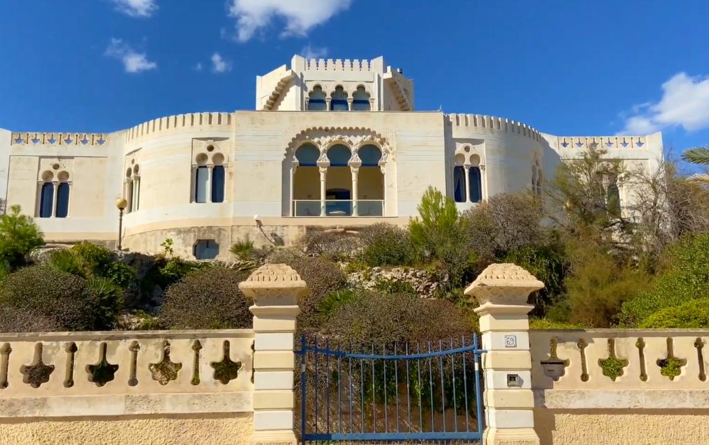 artistic villa with stone walls and archway windows, stone fence and metal gate