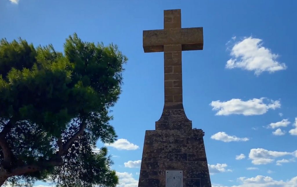 a cross statue near a pine tree