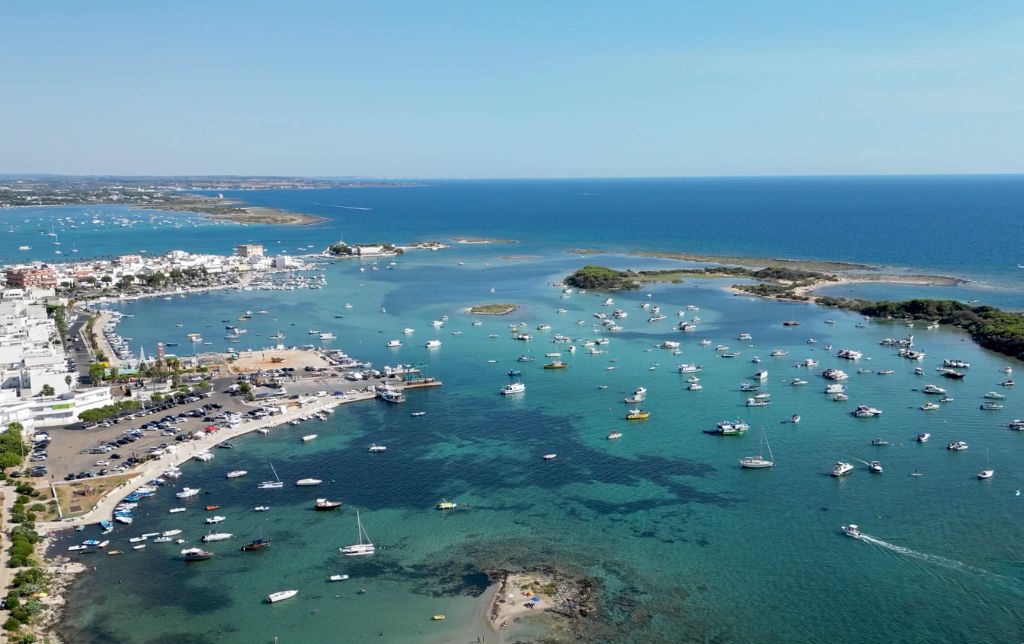 aerial view of three small gulfs full of boats. buildings on the shore and cars parked in a shore parking lot