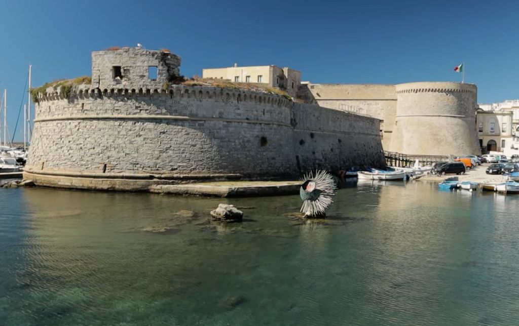 ancient defense tower on the shore, dark green water and boats