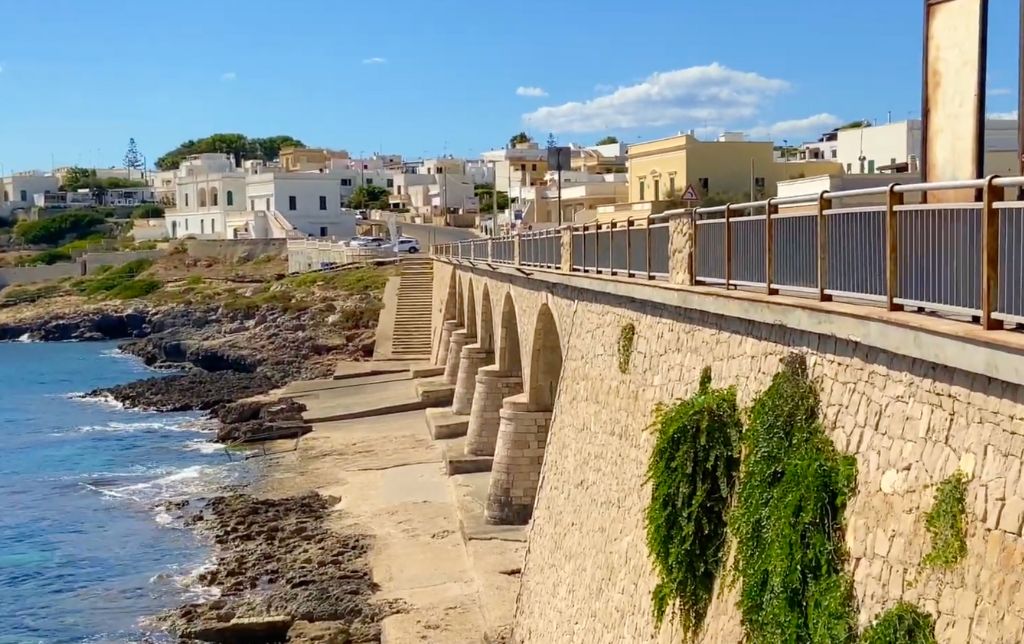 ancient bridge on the shore towards a village with white houses