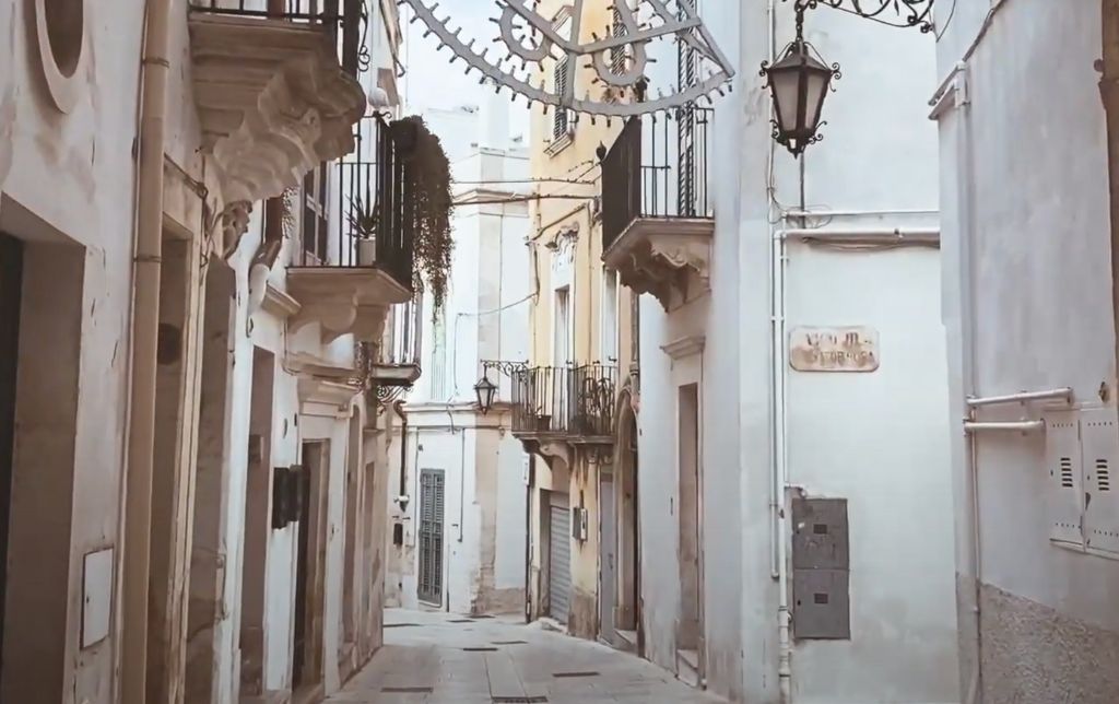 narrow street made of ceramic white tiles guarded left and right by white town houses with small metal balconies