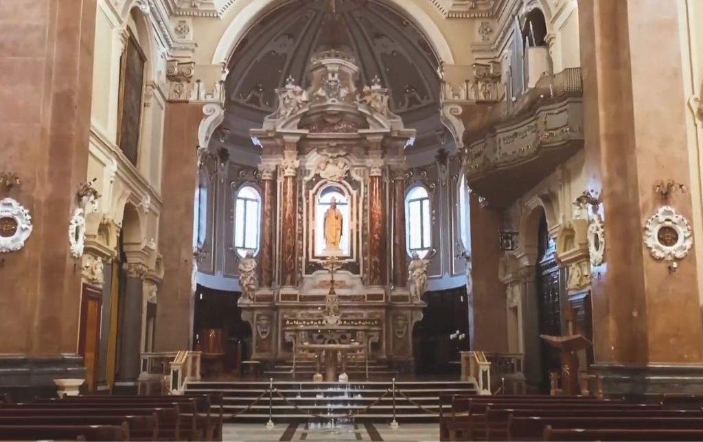 inside catholic church statue and wooden benches