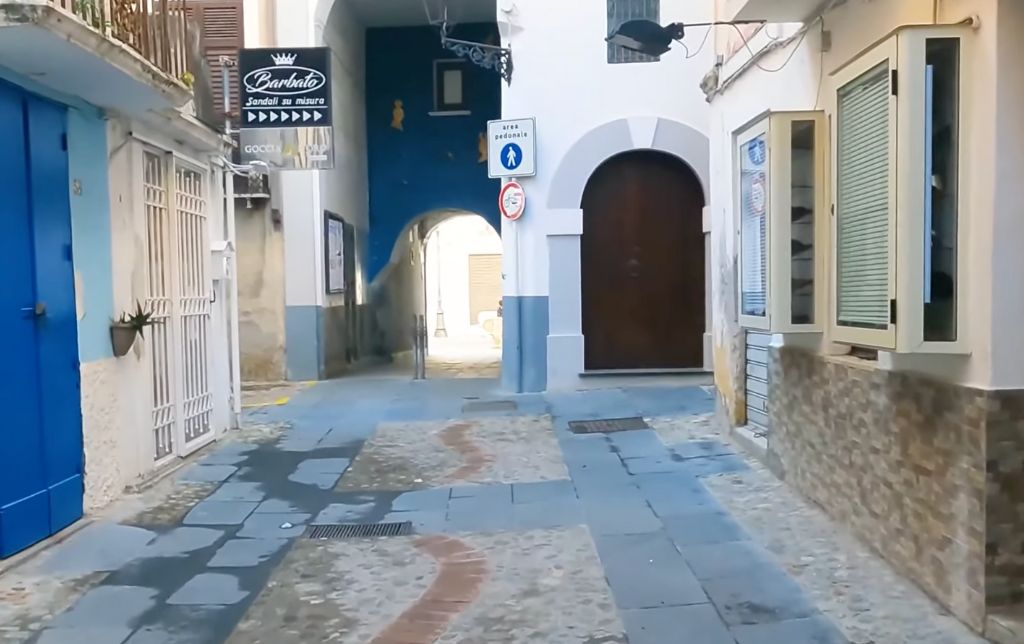 stone and cement road amongst white houses with blue and brown doors
