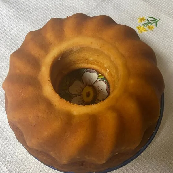 brown golden bundt lemonade cake cooling on a plate, on a white towl