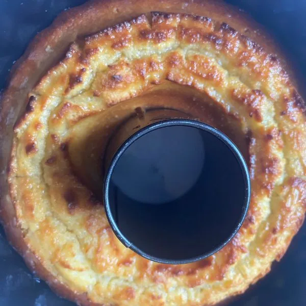 brown golden bundt lemonade cake cooling in a bundt form on a white towel