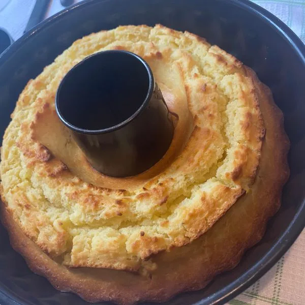 brown golden bundt lemonade cake cooling in a bundt form on a white towel