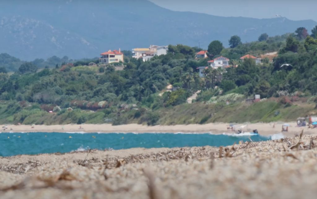 windy blue gulf viewed from afar, houses on top of the hill guarding the gulf beach