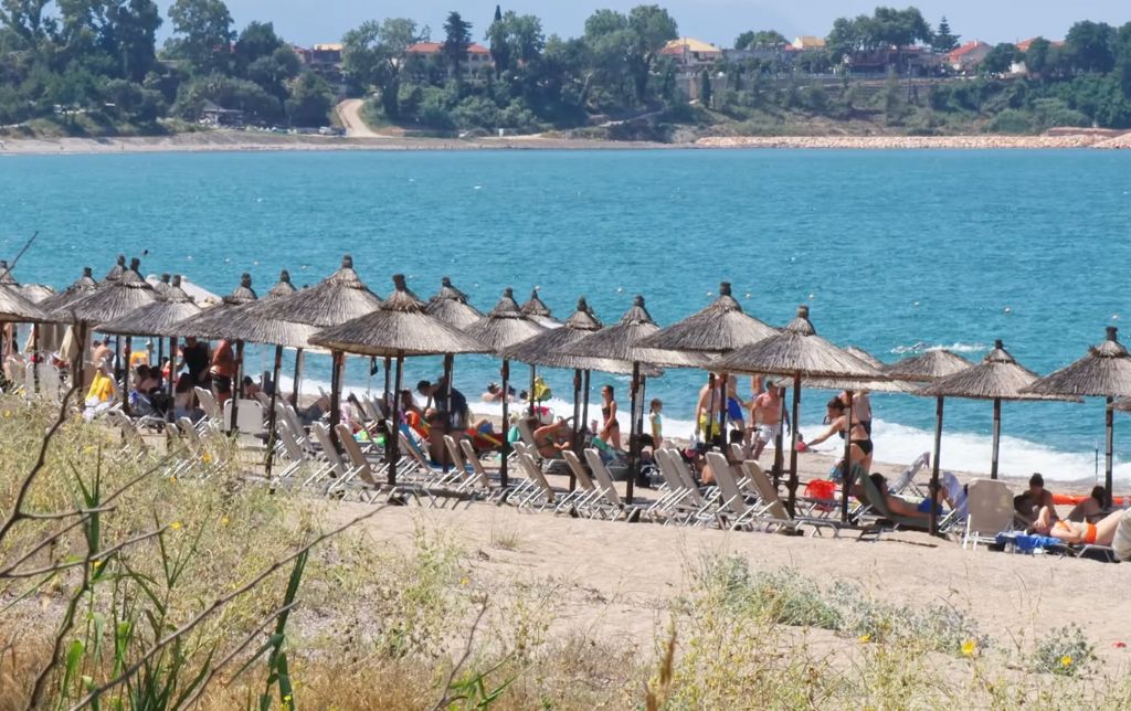 busy sandy beach with umbrellas on the shore of a blue gulf