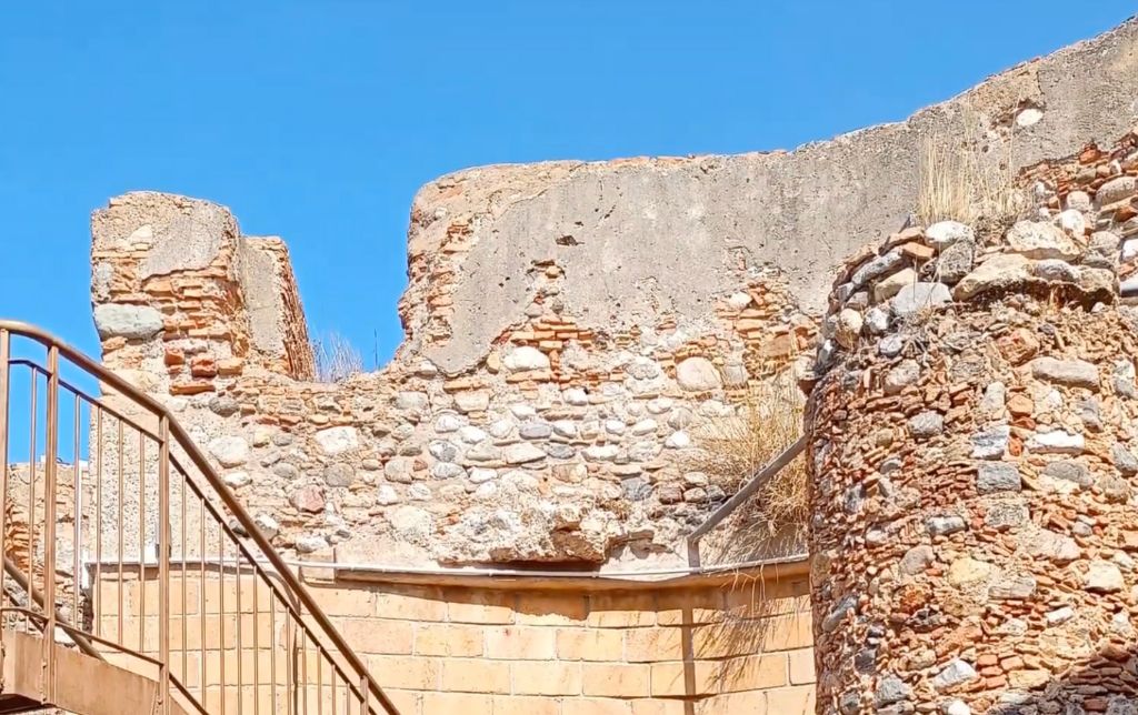stone wall of a ruin with metal stairs in front of it
