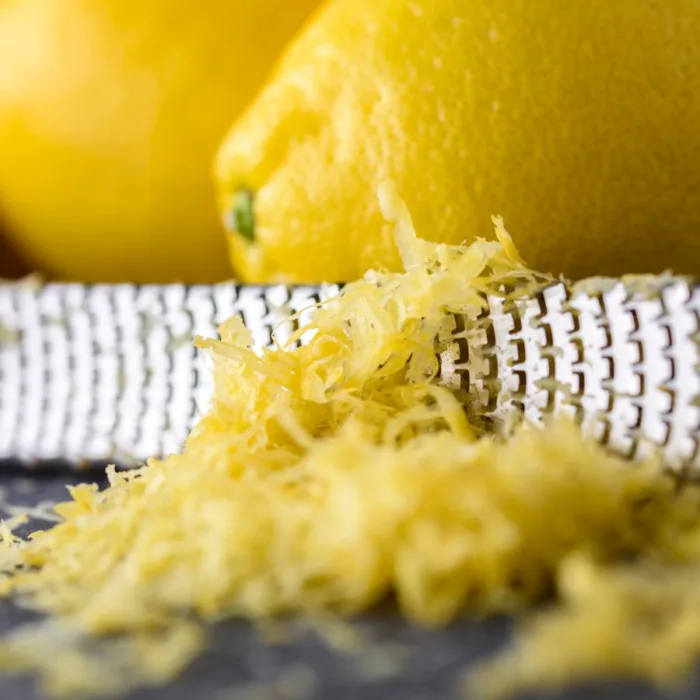 shaved lemon zest on a wooden table near two lemons