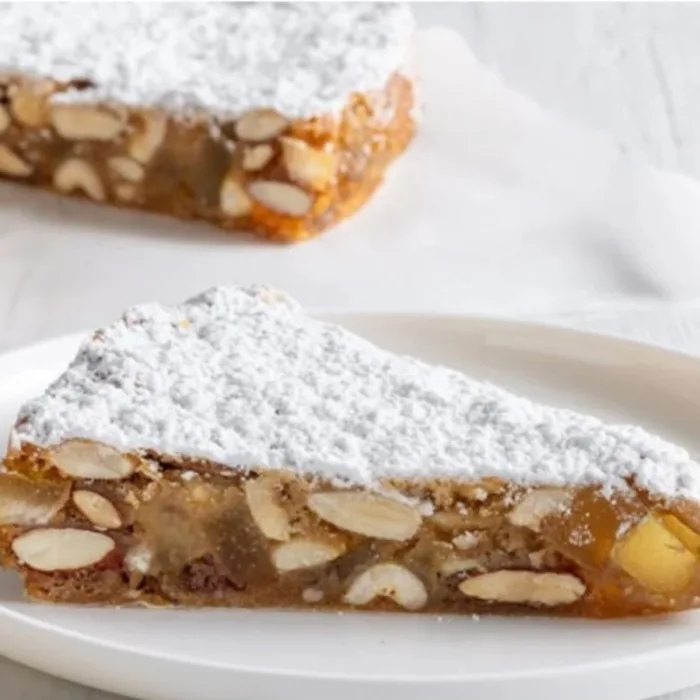 two slices of panforte margherita, one o a white plate the other directly on the white table