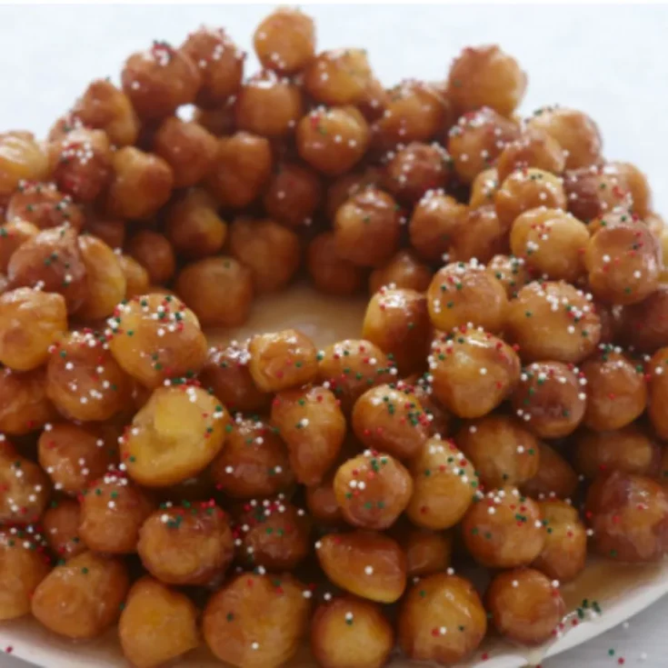 wreath of struffoli on a white tables, sparkled with candied fruits cut very small