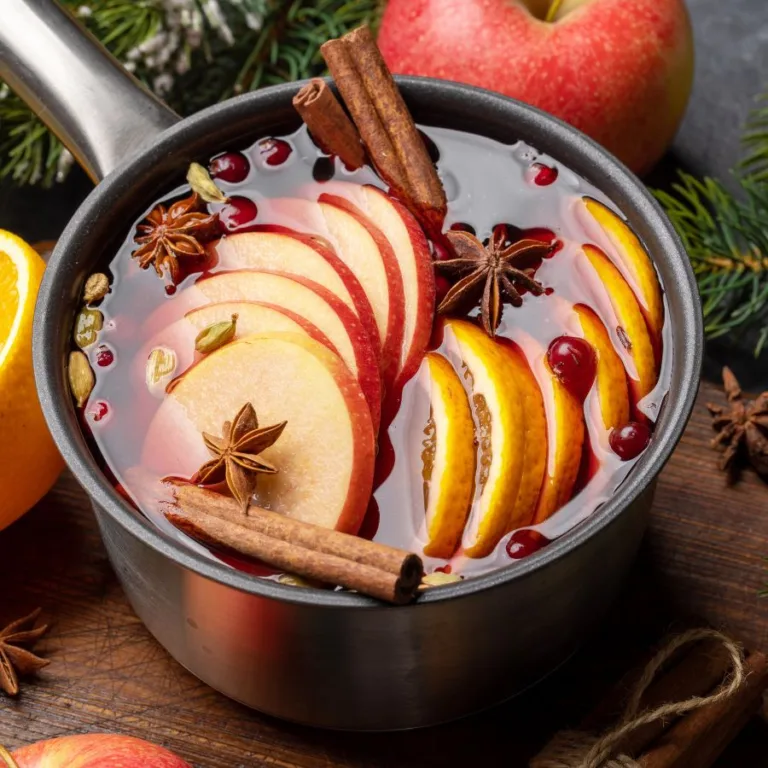 cup with vin brule on a woden table near seasonal fruits (apple, orange)