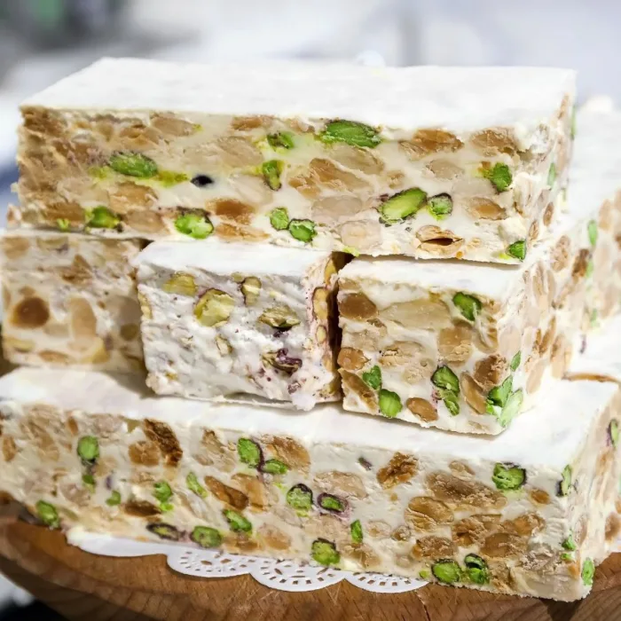 big slices and small cubes of torrone on a wooden table