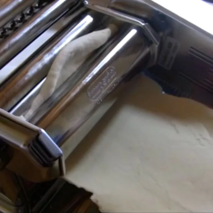 passing dough through a steel pasta machine