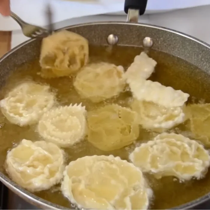 cartellate in a bath of hot oil on a pan on a stove