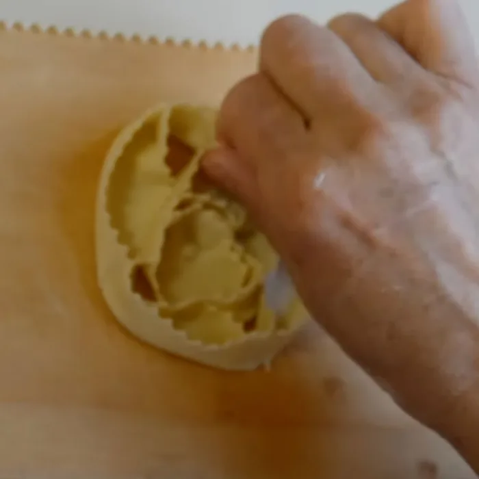 close up of a hand finishing up a cartellata on a wooden table