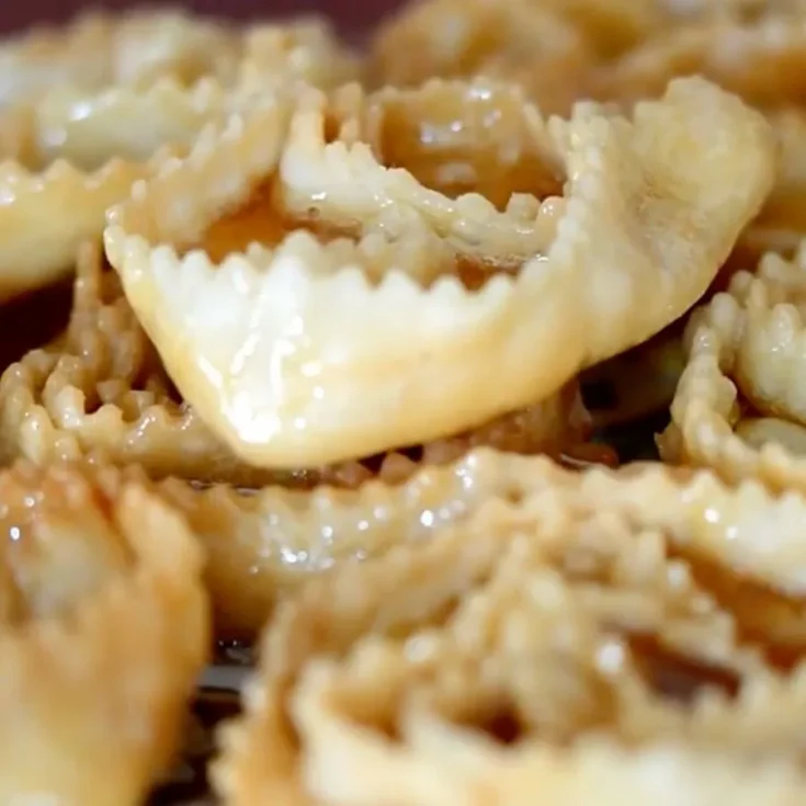 close up of cartellate on a white plate, drenched in honey