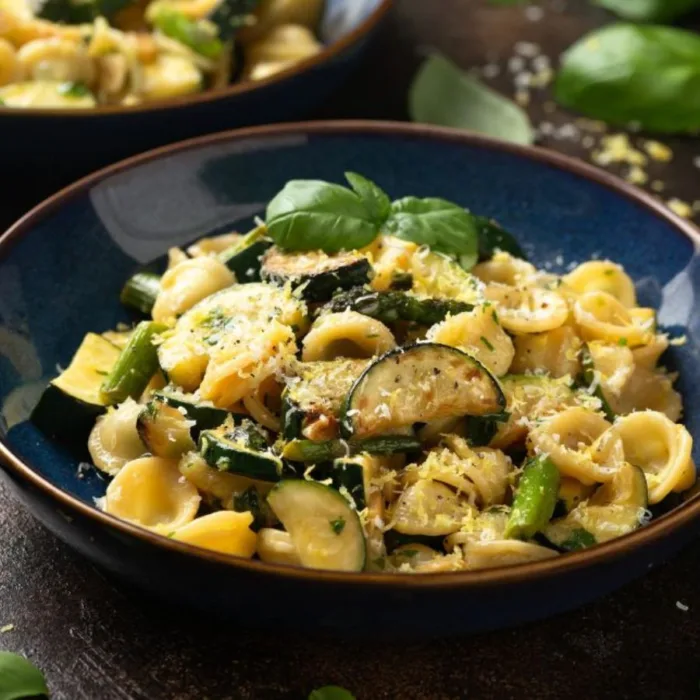 orecchiette con manzo al limone in a black bowl on a wooden table, close to basil bowl