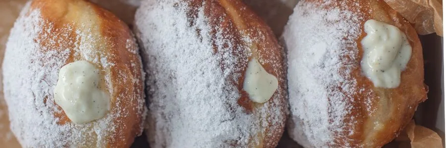 close up of 3 zeppole filled with ricotta in a paper bag