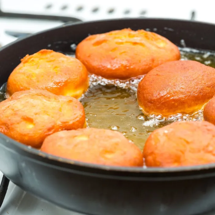 pen with 6 golden donuts frying in hot oil