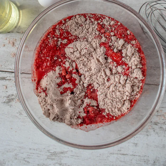 red batter with flour on top in a glass bowl on a marble table