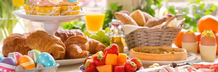 easter table set with red and yellow eggs and bread and cakes