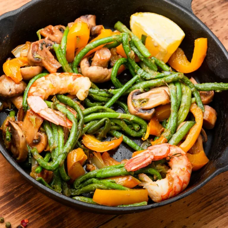 pan of shrimp with asparagus and mushrooms and lemon on a wooden table