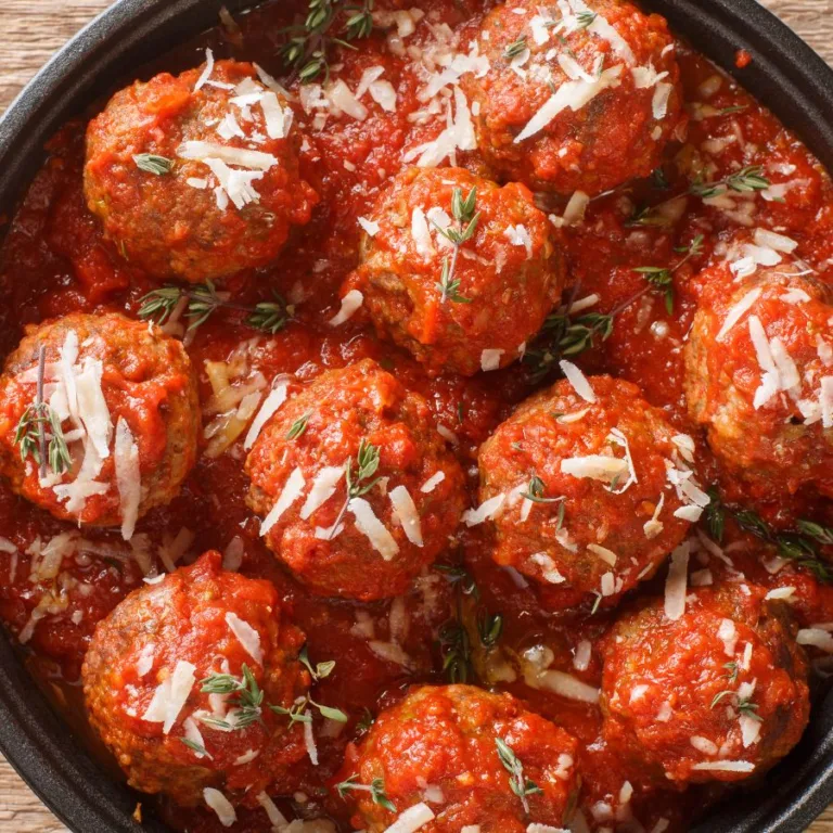 polpete al sugo - tomato sauce meatballs in a pot with shredded cheese on top, sitting on a wooden table