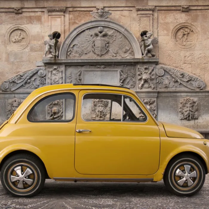 yellow mini car photographed near a street fountain in Rome