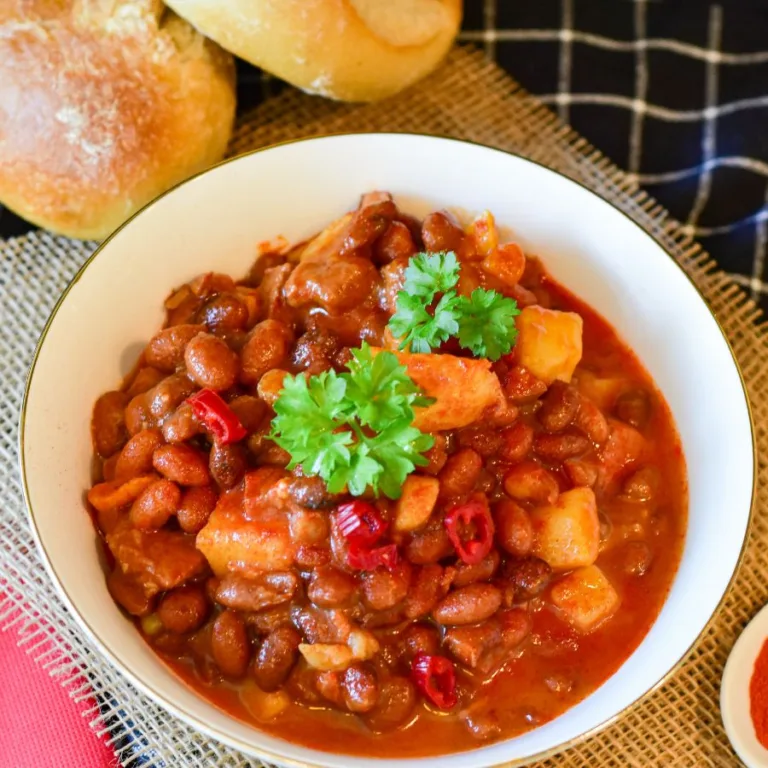 cannellini beans in a white bowl sitting on a table near bread crutons